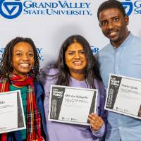 three individuals smiling holding certificates